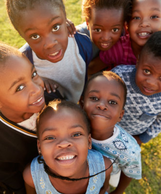 Elementary school kids in a field look up at camera smiling