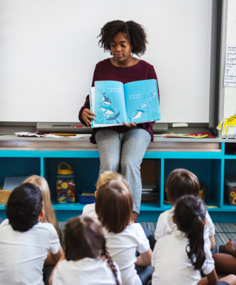 Kindergarden student sitting on the floor listening